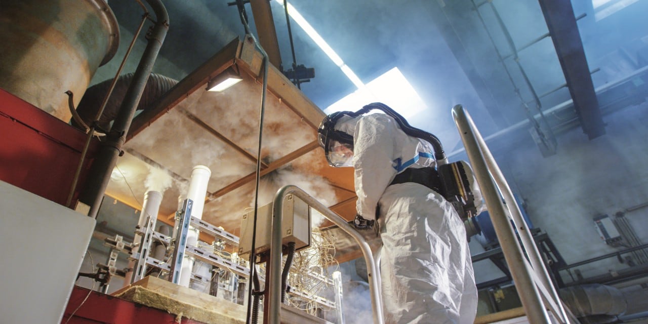 Védőruhába öltözött munkatárs dolgozik egy laboratóriumban