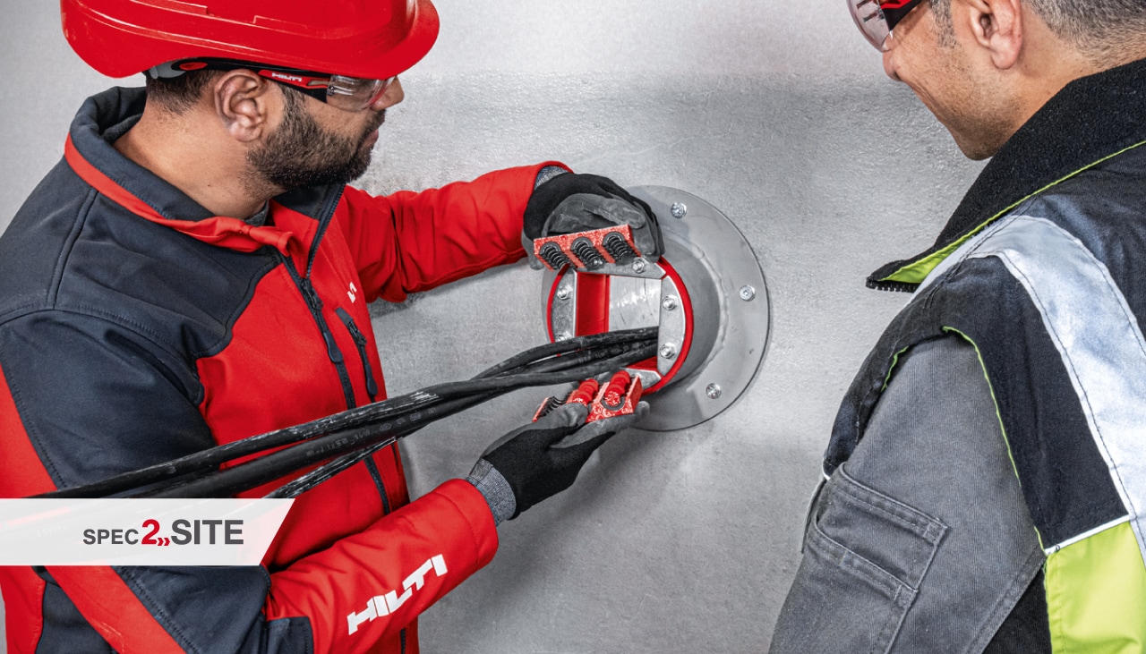 a Hilti mérnöke a helyszínen bemutatja az ügyfélnek egy tűzgátló hüvelyt egy elektromos alkalmazásban